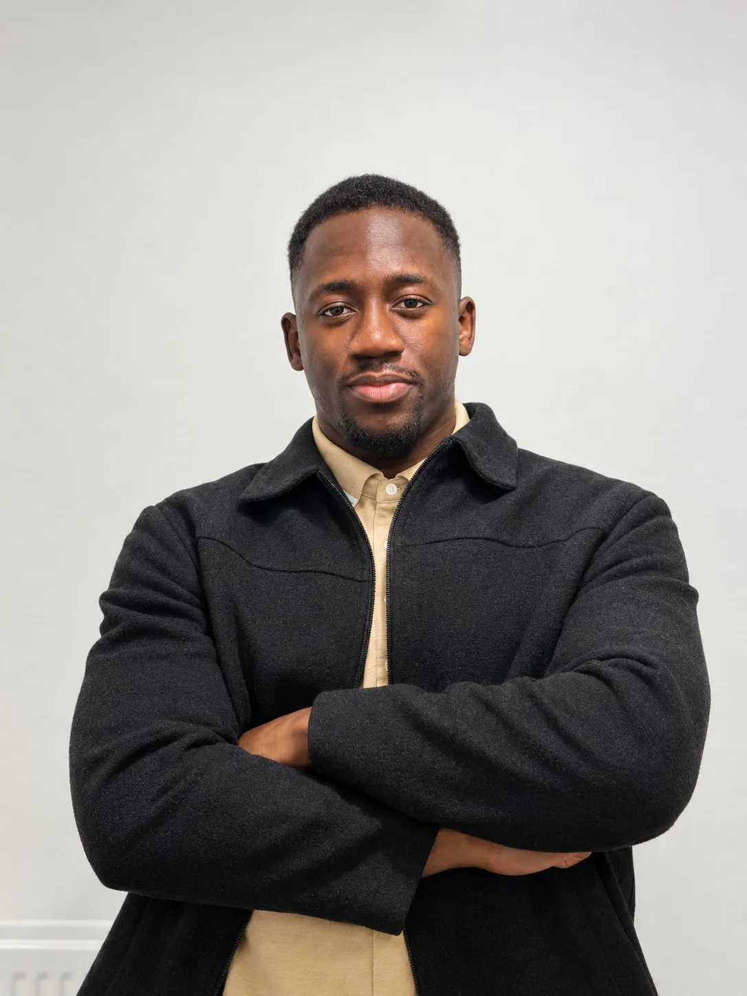 Ibrahim Adeshina, arms folded, in a black jacket over a beige shirt